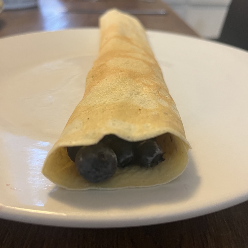 The finished Pönnukökur stuffed with blueberries and rolled on a plate.