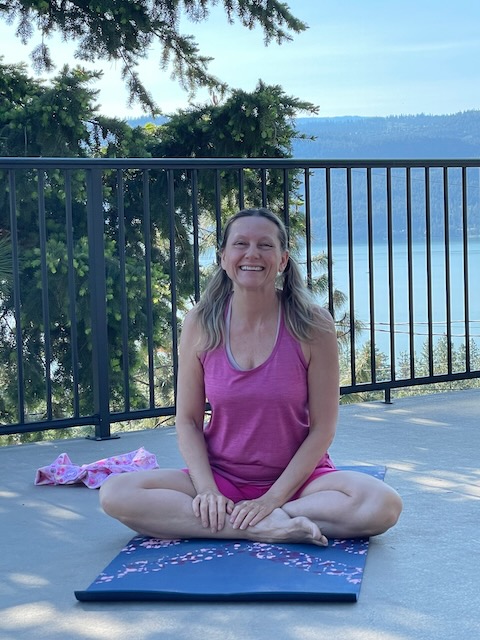 Author Dani Collins ready to do yoga. Behind her, you can see a a beautiful lake and lots of trees.
